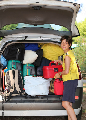 child loads bags in the baggage car in summer