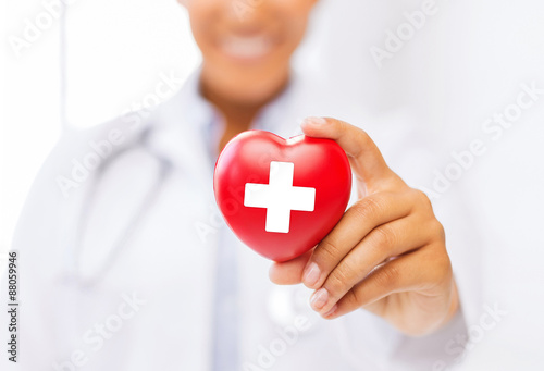 Canvas-taulu female doctor holding heart with red cross symbol