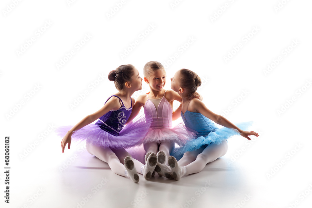 Three little ballet girls sitting in tutu and posing together