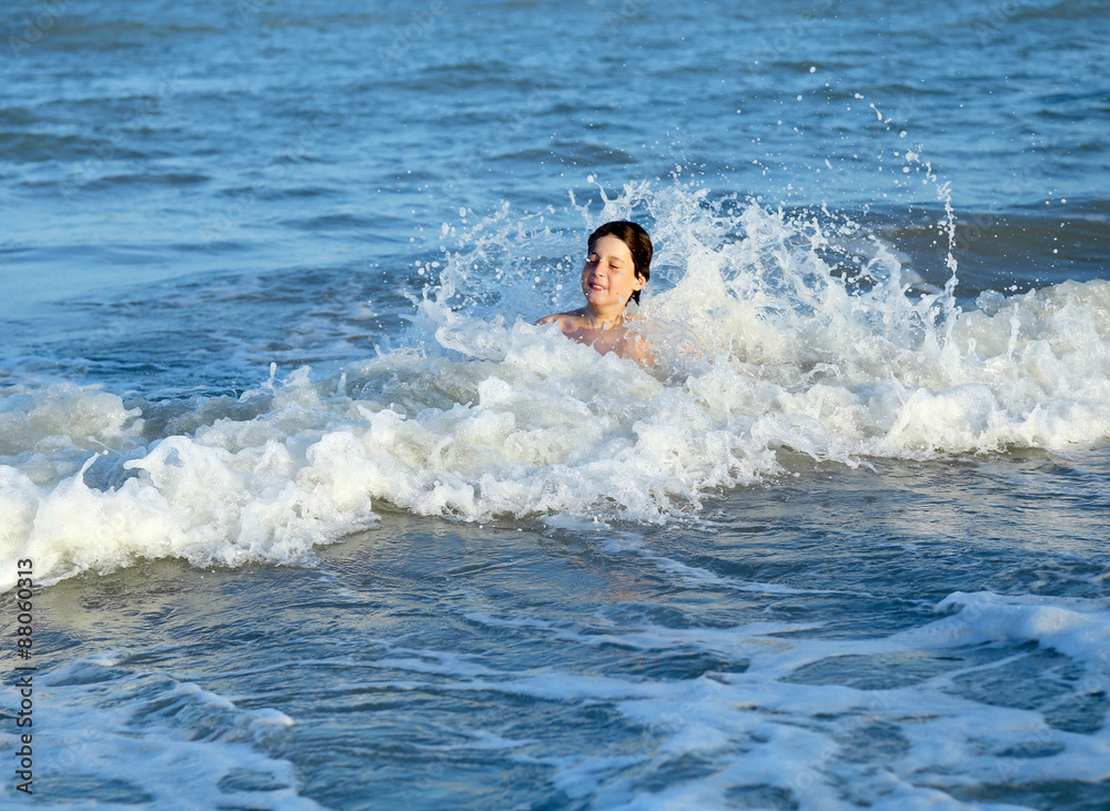 child SPLASHING in the waves of the sea in summer