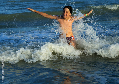 young boy makes SPLASHING in the waves of the sea in summer © ChiccoDodiFC