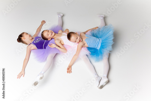 Three little ballet girls in tutu lying and posing together