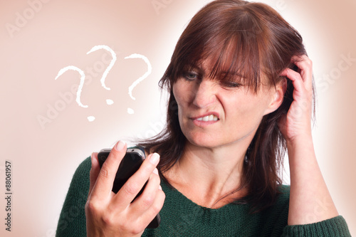 Frau schaut fragend auf das Smartphone und kratzt sich den Kopf