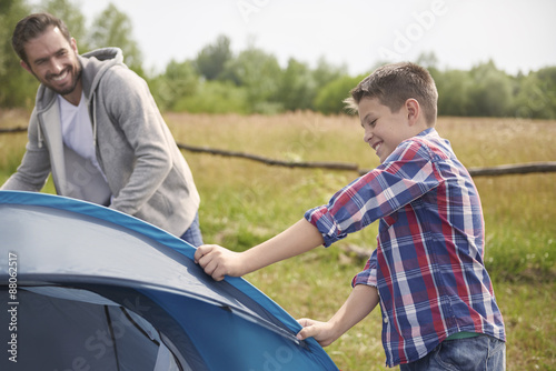 Son helping his father on the camping