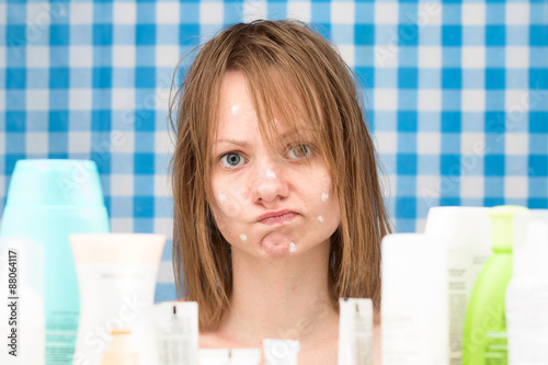 Portrait of upset cute girl with problem face skin in bathroom