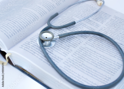 Stethoscope old put on a thick textbook content in a blur.
