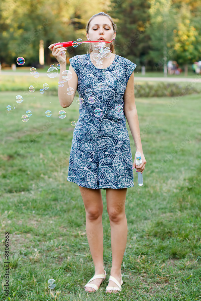 Fototapeta premium Beautiful girl in the park with soap bubbles.