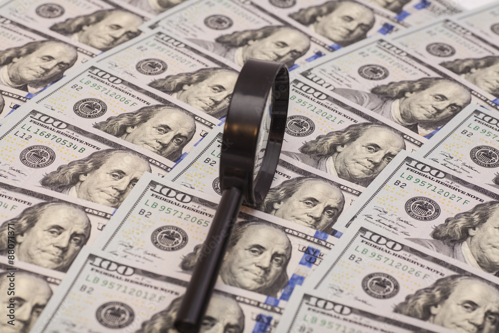 Hundred dollar banknotes under magnifying glass Hundred dollar banknotes under magnifying glass