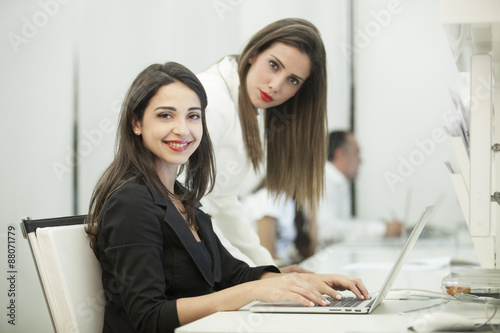 Due belle e giovani impiegate lavorano al pc in ufficio photo