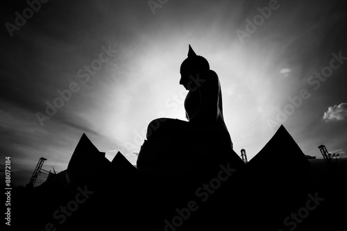 Silhouette buddha statue in sunset background.