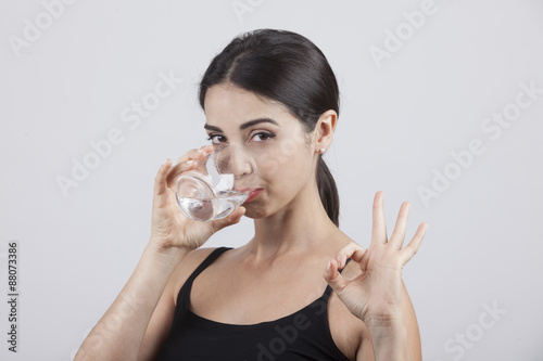 Giovane e bella ragazza beve un bicchiere d'acqua photo