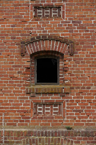 Old small window with red brick in the wall of an old warehouse.