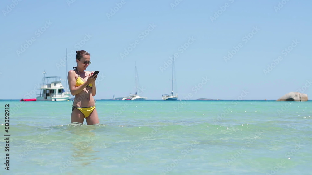 Brunette girl reading or writing sms on sea background at the beach Brunette girl reading or writing sms on sea background at the beach