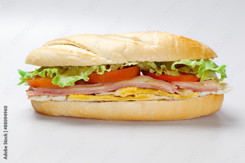 Sandwich on a white plate with turkey breast, tomato and lettuce.