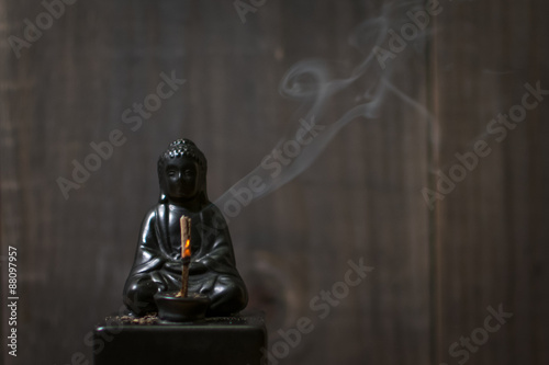Burning Incense on Buddha Statue with Curling Smoke photo
