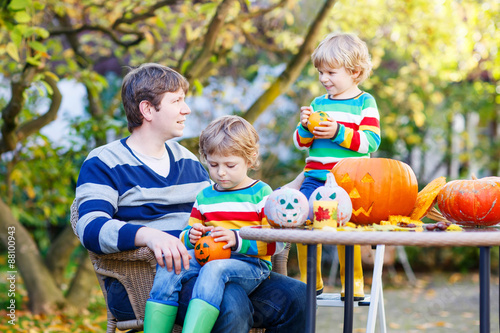 Young dad and two little kids making jack-o-lantern