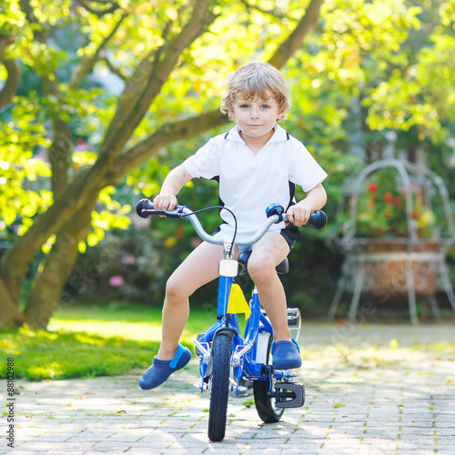 Fototapeta Naklejka Na Ścianę i Meble -  Little preschool kid boy riding with bicycle in summer
