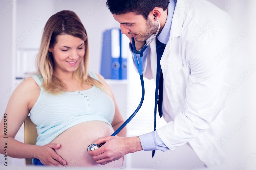 Smiling doctor examining stomach of pregnant patient Smiling doctor examining stomach of pregnant patient