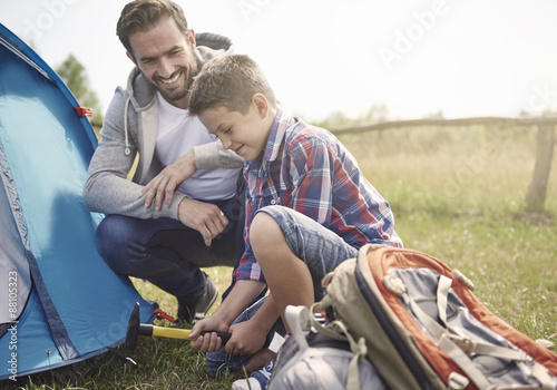 Father teaching son how to pitch a tent