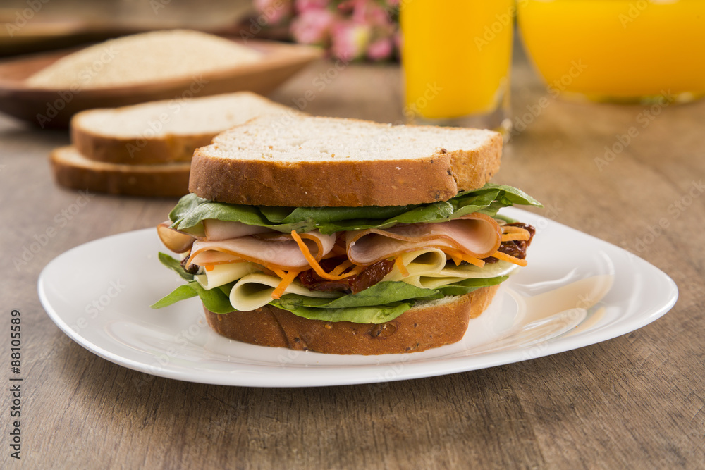Sandwich on a white plate with turkey breast, tomato and lettuce Sandwich on a white plate with turkey breast, tomato and lettuce