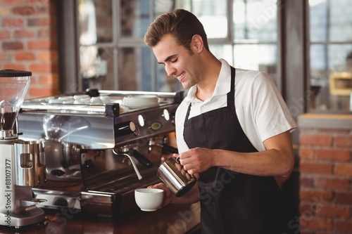 Obraz na płótnie Smiling barista pouring milk into cup