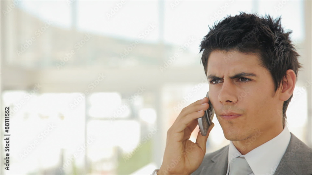 Panning shot of serious businessman answering smart phone. Male executive is in suit. Smart well-dressed professional is on call in brightly lit office. Panning shot of serious businessman answering smart phone. Male executive is in suit. Smart well-dressed professional is on call in brightly lit office.