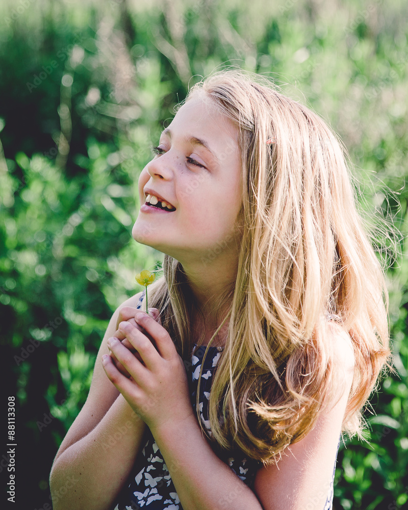 Portrait of a smiling girl holding a buttercup under her chin Stock