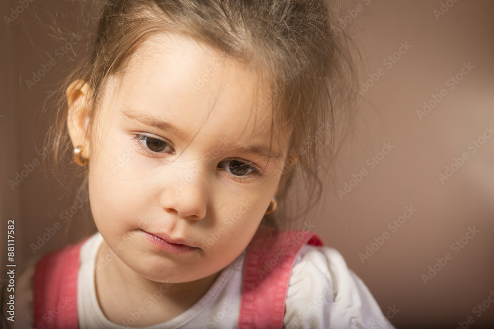 Expressive little girl, melancholic, thinking away, studio shot on brown background Expressive little girl, melancholic, thinking away, studio shot on brown background