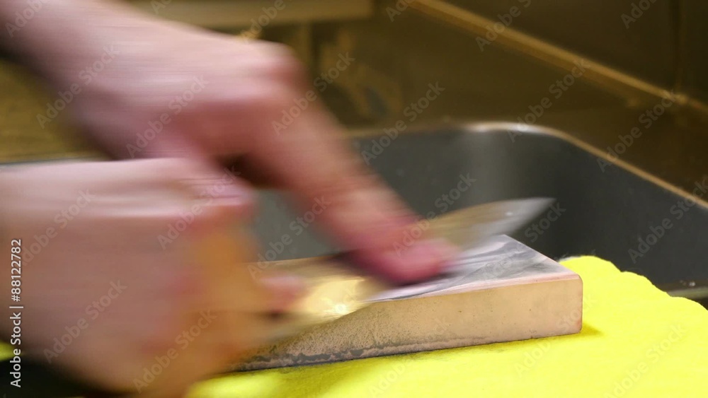 Sushi Chef Sharpening his Knife with a Pink Stone. Professional chef