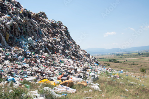 Landfill near crop fields. Enormous Trash wave near fields