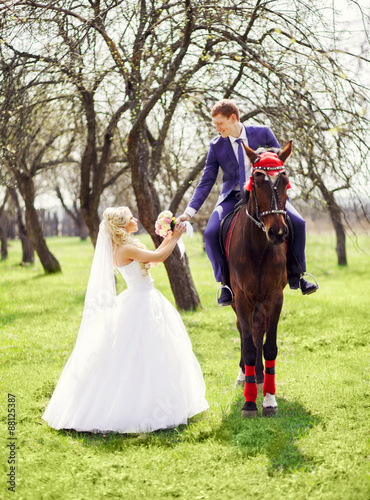 groom on a horse gives the bride's bouquet in the spring, apple © Aleksey Sergeychik