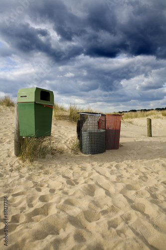 Three waste bins on a beach.