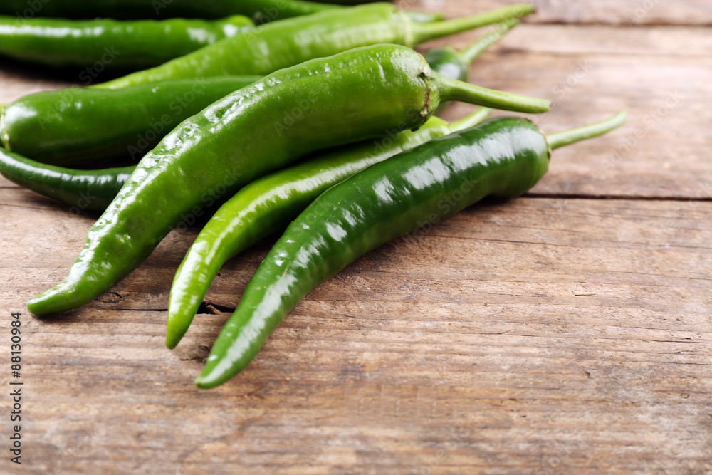 Green hot peppers on wooden table close up Green hot peppers on wooden table close up