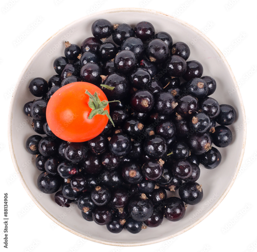 Isolated black currant with tomato on saucer Isolated black currant with tomato on saucer