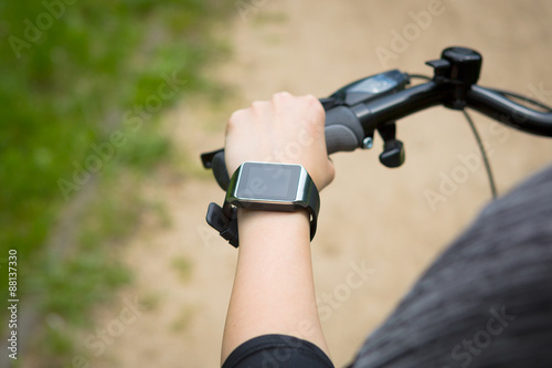 Woman riding a bike with a smartwatch heart rate monitor.