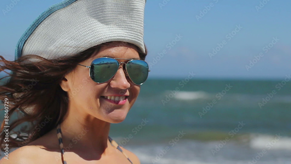Professional female model posing for photo shoot on sea beach, smiling at camera Professional female model posing for photo shoot on sea beach, smiling at camera