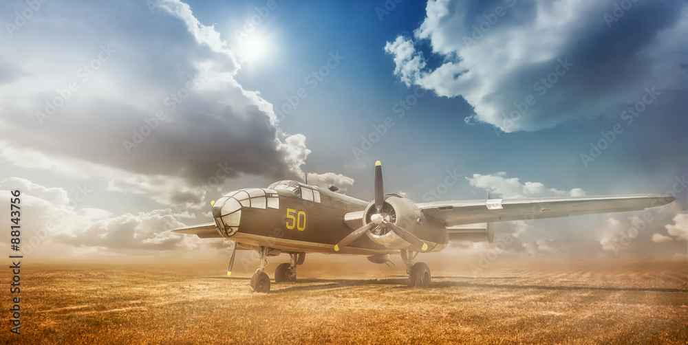 Fototapeta premium Old bomber in cloud of dust in the open field