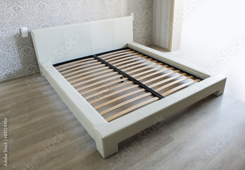 Bed in bedroom with wooden slats without mattress