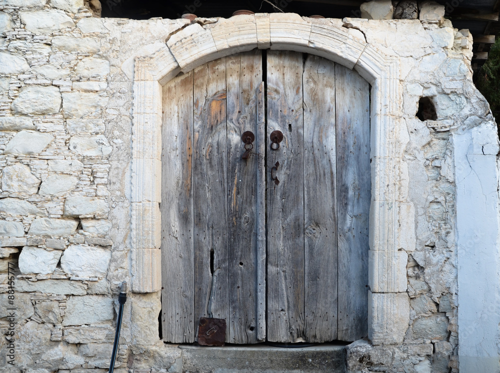 Cyprus Old wooden door with surrounding white stone fixed on dry stone wall in Cyprus.