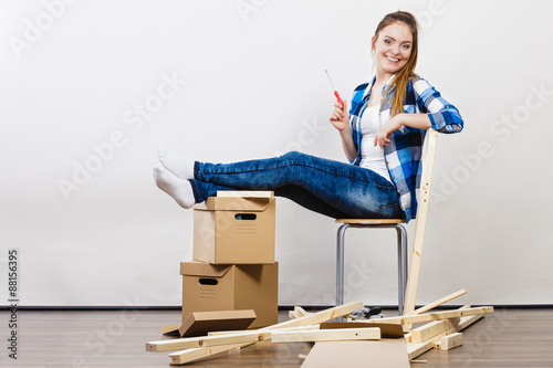 Woman moving into apartment assembly furniture. photo