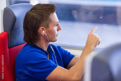 Young caucasian man listening music look at window traveling by