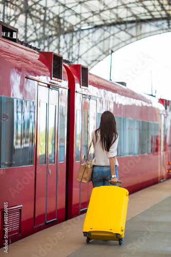 Young caucasian woman with luggage at station traveling by train photo