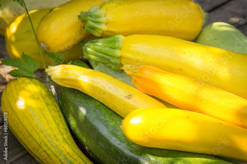 yellow, green zucchini on the old wooden table top, in a wicker