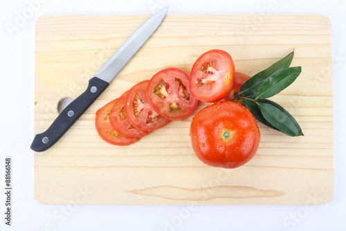 tomatoes cut by a kitchen knife on a wooden board