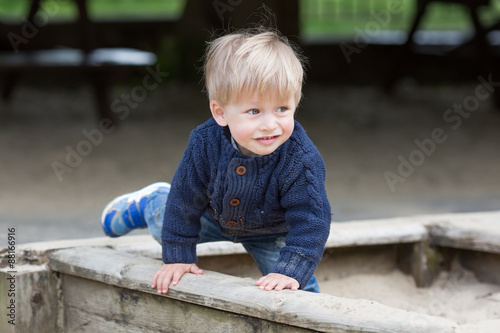 Little baby boy outdoors playing in sandbox.