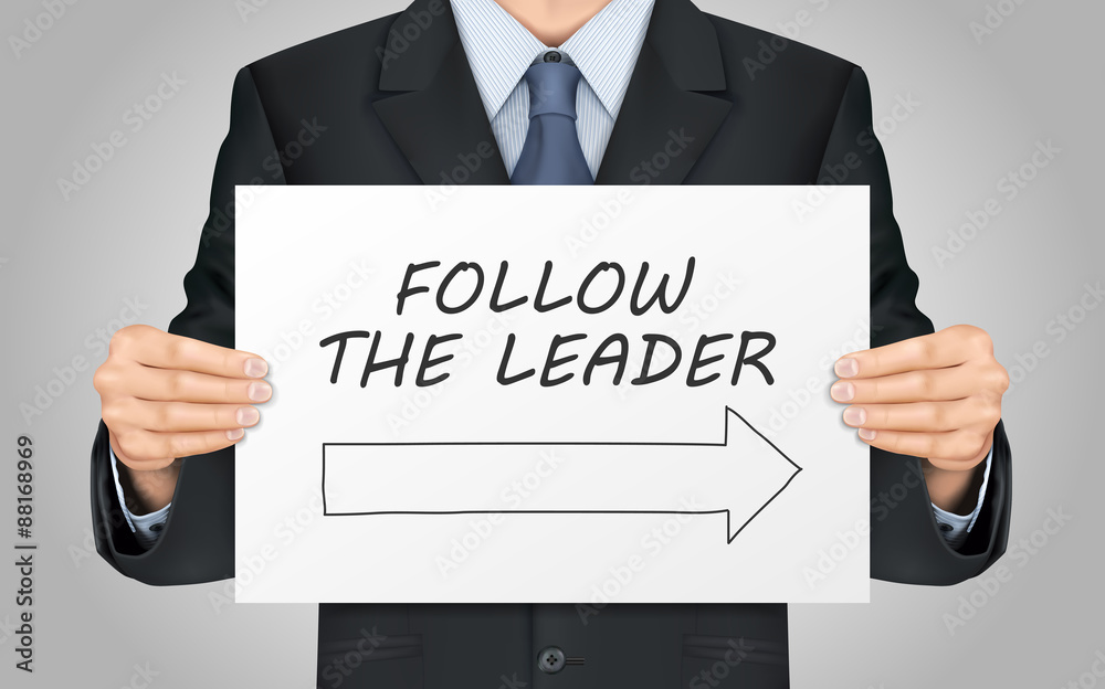 businessman holding follow the leader poster