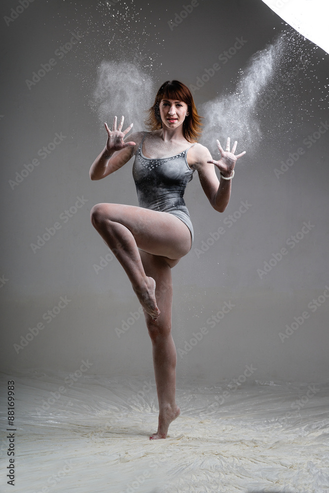 Beautiful expressive ballet dancer posing with flour at studio