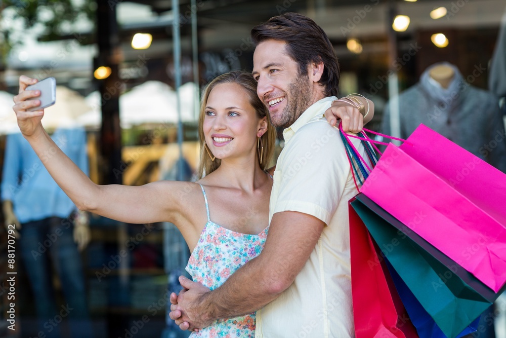 Smiling couple embracing and taking selfies Smiling couple embracing and taking selfies