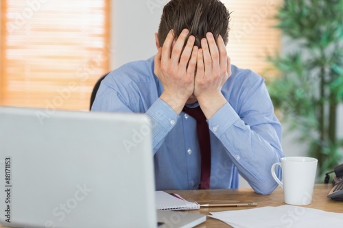 Stressed businessman with head in hands