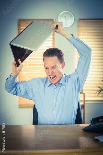 Furious businessman about to smash his laptop